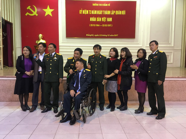  Anh Cẩn (ngồi xe) và vợ (người thứ 3 bìa phải) đang giao lưu cùng Ban giám hiệu Trường THCS Giảng Võ và khách mời nhân ngày thành lập Quân đội Nhân dân Việt Nam (22/12). ảnh : Minh Anh 