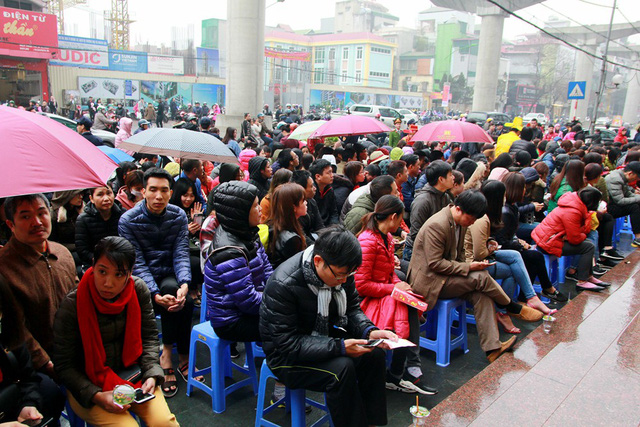 Tại Cừa hàng Bảo Tín Minh Châu (319 Cầu Giấy, Hà Nội) hàng dài người xếp hàng dưới mưa chờ mua vàng cầu may.