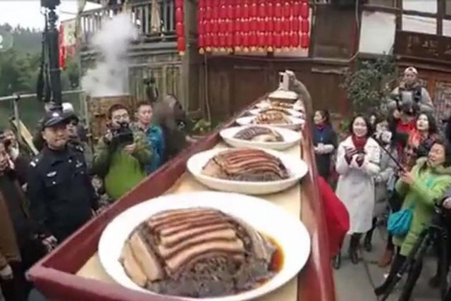Những người phục vụ đặt một khay thức ăn dài 2m chứa đầy các món ăn trên đầu và phục vụ tại bữa tiệc ở Trùng Khánh, Trung Quốc