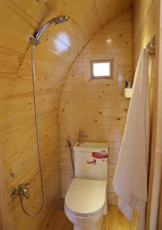 Nhà vệ sinh đầy đủ thiết bị với vòi sen, bồn cầu kết hợp bồn rửa tay phía trên.