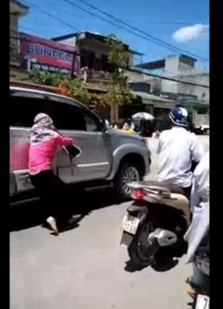  Người phụ nữ áo hồng (được cho là bạn của người vợ) cố gắng ngăn chặn chiếc xe dừng lại. Ảnh cắt từ clip.