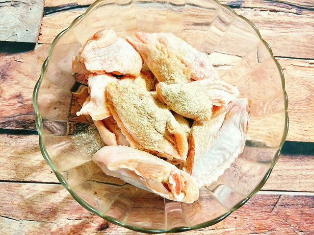 Cho cánh gà vào tô cùng với bột canh, hạt nêm, tiêu, bột tỏi rồi xóc đều, ướp cánh gà 30 phút cho ngấm gia vị.