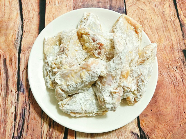 Cho bột nở, bột mì vào túi bóng và trộn đều sau đó cho cánh gà vào xóc đều để cánh gà bám một lớp bột bên ngoài.