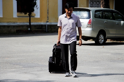 Một giảng viên Trường Đại học Khoa học Huế mang theo vali chuẩn bị lên xe đi Quảng Bình coi thi. Ảnh: Võ Thạnh