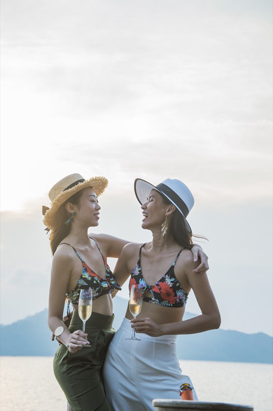 Áo bơi hoạ tiết hoa lá nhiệt đới được hai người đẹp sử dụng cùng quần ống rộng lưng cao. Set trang phục phù hợp với những buổi tiệc chiều trên bờ biển vắng.