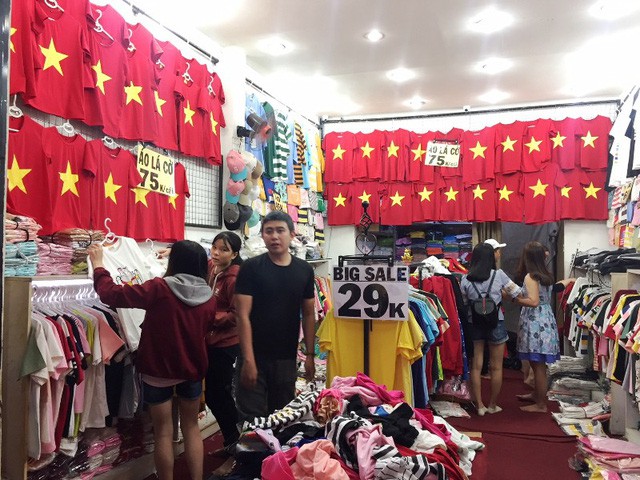 “Mấy hôm nay, rất nhiều khách đến mua áo thun đỏ sao vàng năm cánh về cổ vũ bóng đá. Sau trận thắng của tuyển Việt Nam ở tứ kết thì lượng khách đến mua hàng tăng gấp 3 lần so với ngày bình thường. Mỗi ngày, chúng tôi bán ra khoảng 300 áo”, chị Châu nói. Ảnh: Dân Trí.