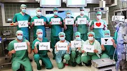 Các y bác sĩ trên toàn thế giới đồng loạt giơ cao thông điệp ý nghĩa: "Chúng tôi đang làm việc vì các bạn còn các bạn hãy ở nhà vì chúng tôi"