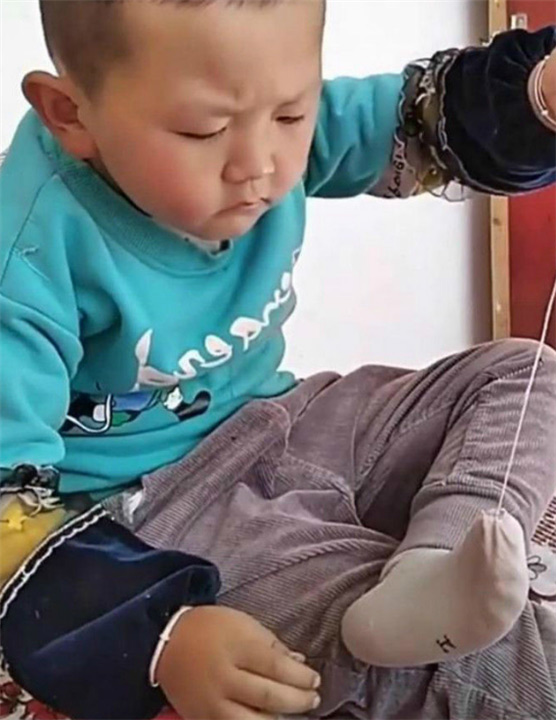 Cậu bé gây chú ý khi tự ngồi khâu tất, biểu cảm rất đáng yêu - Ảnh 1. Cậu bé gây chú ý khi tự ngồi khâu tất, biểu cảm rất đáng yêu - Ảnh 1.
