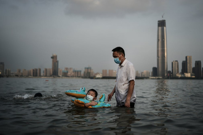 24h qua ảnh: Cậu bé đeo khẩu trang bơi trong công viên ngập lụt do nước sông dâng cao ở TQ - Ảnh 2.