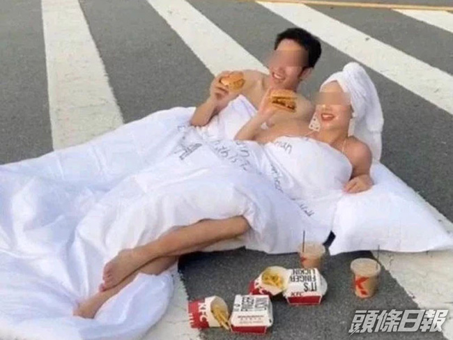 Cặp đôi nhận gạch đá khi diện trang phục gây sốc và biến lòng đường thành chiếc giường để chụp ảnh cưới - Ảnh 1.